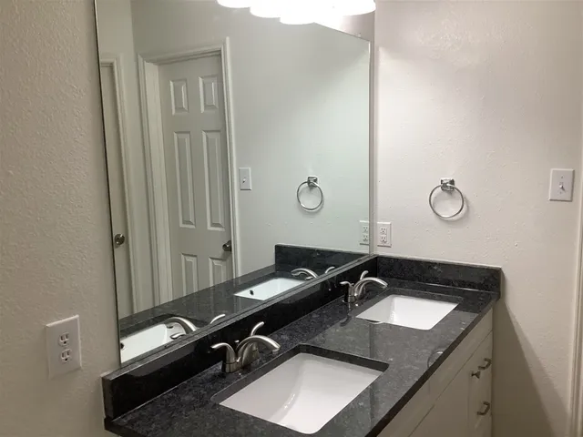 a bathroom with a granite countertop sink and a mirror