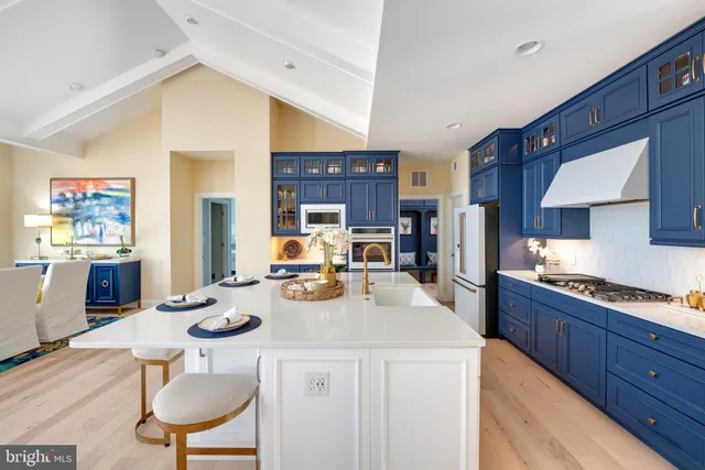 a kitchen with stainless steel appliances kitchen island granite countertop a sink a stove a refrigerator cabinets and chairs