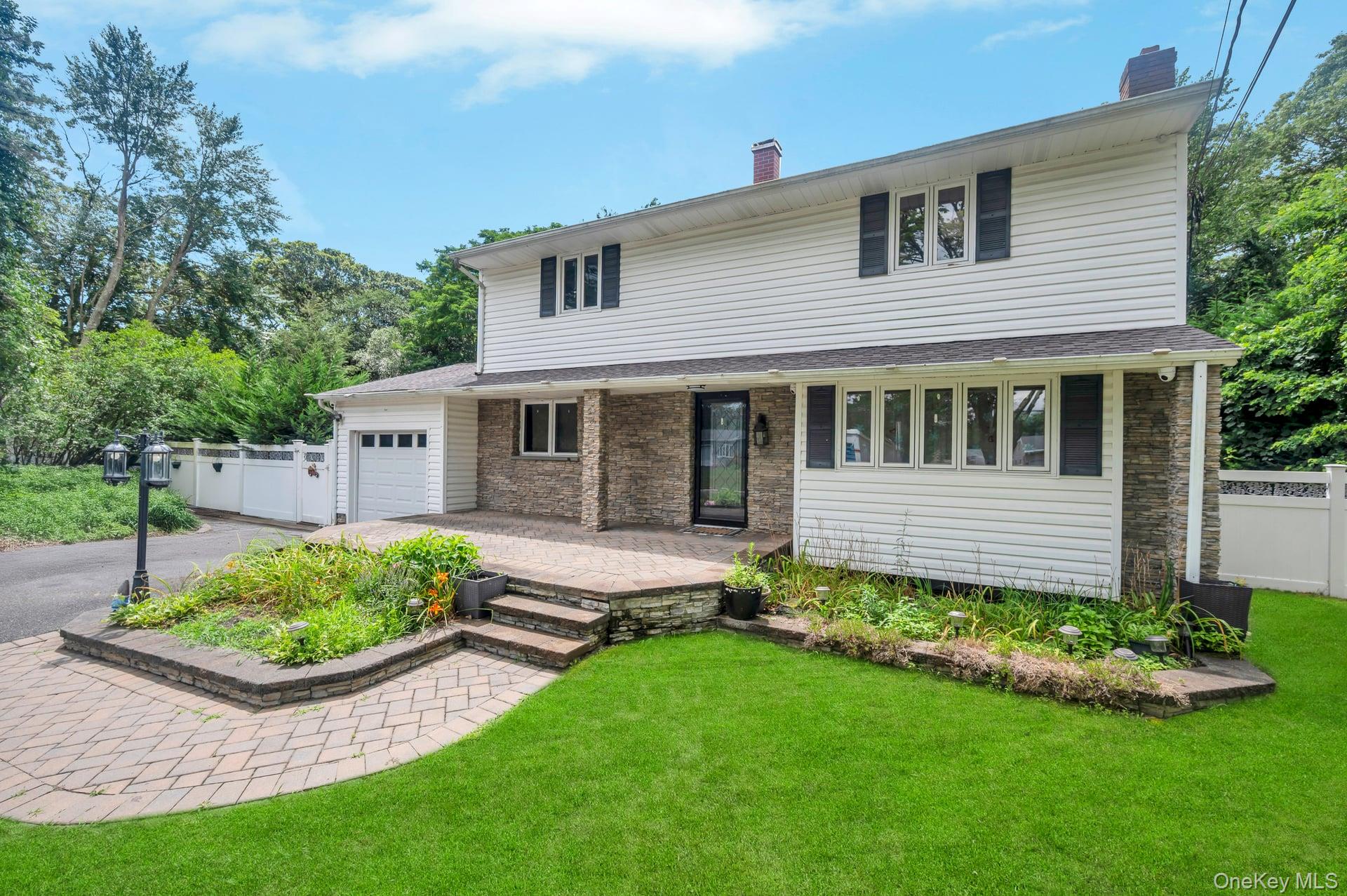 8 Brenner Road Coram, NY 11727 - Photo 18 of 18 Traditional-style home featuring a chimney, a garage, driveway, and covered porch