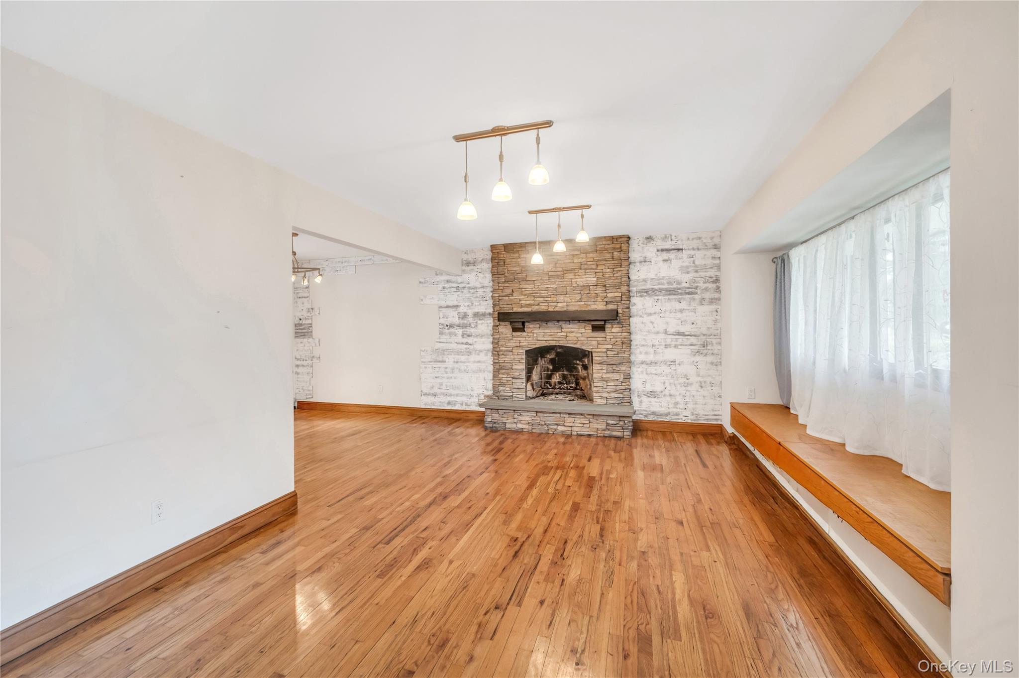 8 Brenner Road Coram, NY 11727 - Photo 4 of 18 Unfurnished living room featuring hardwood / wood-style floors, a fireplace, and rail lighting