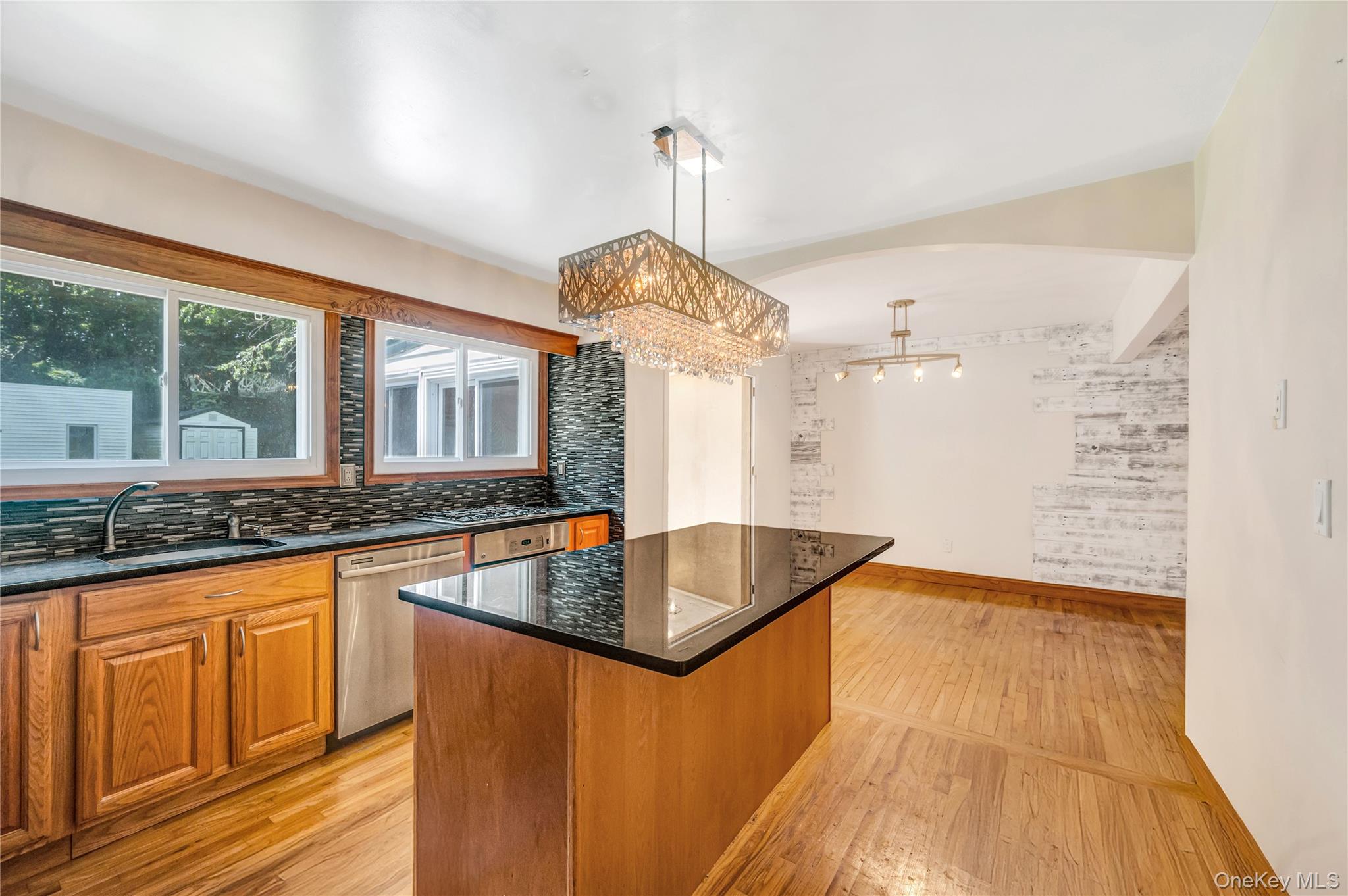 8 Brenner Road Coram, NY 11727 - Photo 7 of 18 Kitchen featuring stainless steel dishwasher, a kitchen island, light wood-style flooring, backsplash, and decorative light fixtures