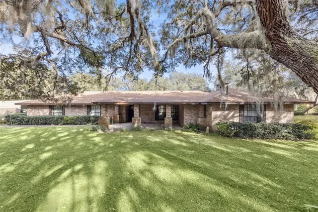 a view of a big house with a big yard and large tree