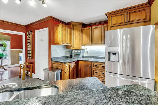 a kitchen with stainless steel appliances granite countertop a refrigerator a stove and a sink
