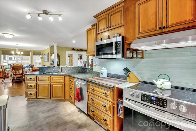 a kitchen with stainless steel appliances granite countertop a stove a sink and a microwave