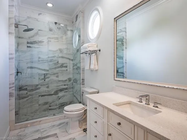 a bathroom with a granite countertop sink toilet a mirror and shower