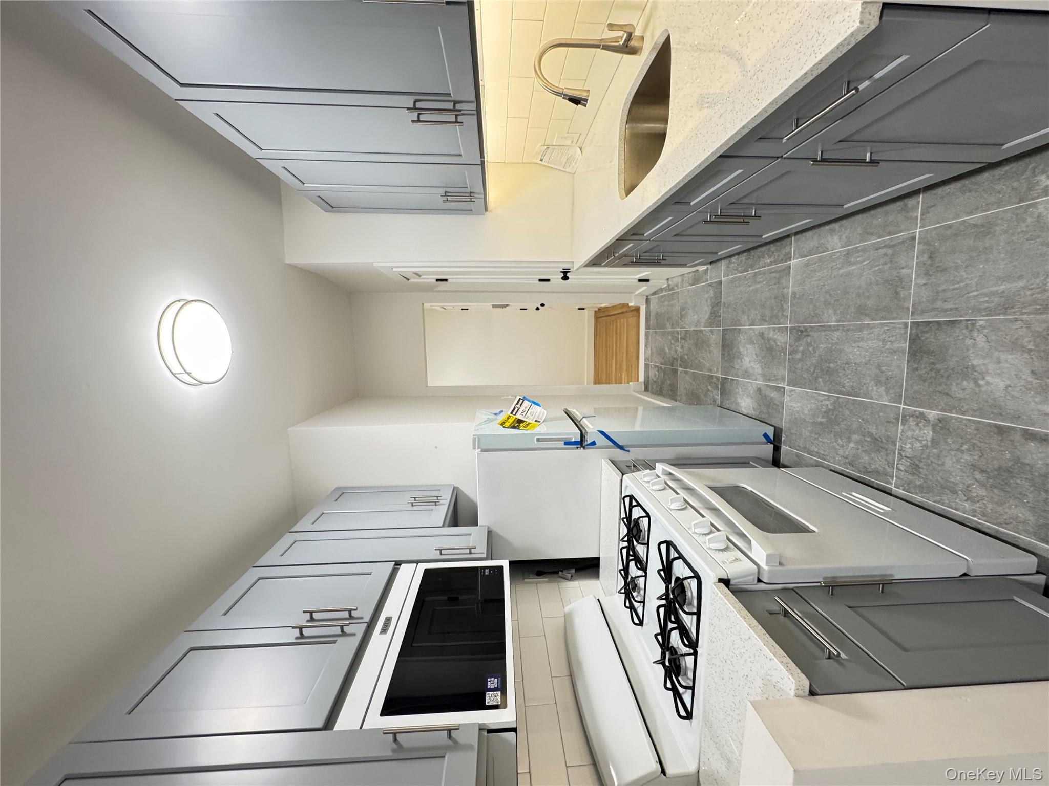 2925 Matthews Avenue, Unit 2H Bronx, NY 10467 - Photo 2 of 6 Kitchen featuring decorative backsplash, gray cabinets, range, and light stone countertops
