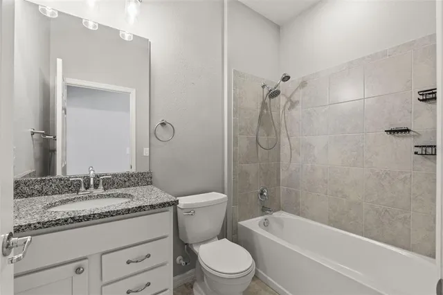 a bathroom with a granite countertop toilet a sink and a bathtub