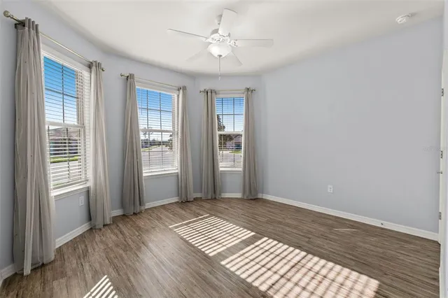 a view of an empty room with window and wooden floor