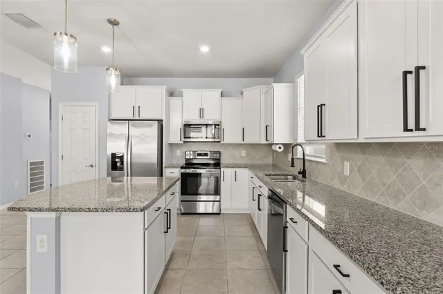 a kitchen with kitchen island granite countertop a sink a counter top space stainless steel appliances and cabinets