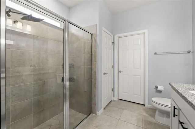 a bathroom with a granite countertop mirror a toilet and a shower