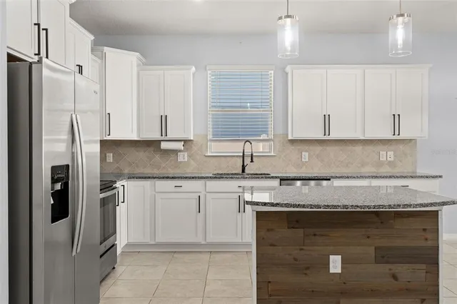 a kitchen with granite countertop a sink stainless steel appliances and cabinets