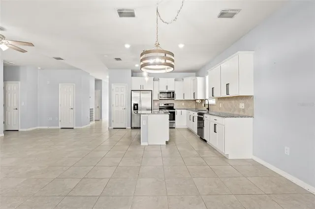 a large white kitchen with lots of counter space cabinets and appliances