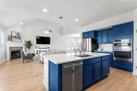 a kitchen with stainless steel appliances granite countertop a stove a sink a refrigerator and a dining table with wooden floor