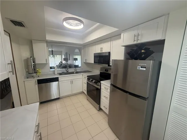 a kitchen with a sink a refrigerator a microwave and cabinets