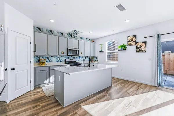 a room with kitchen island stainless steel appliances a stove a refrigerator and cabinets