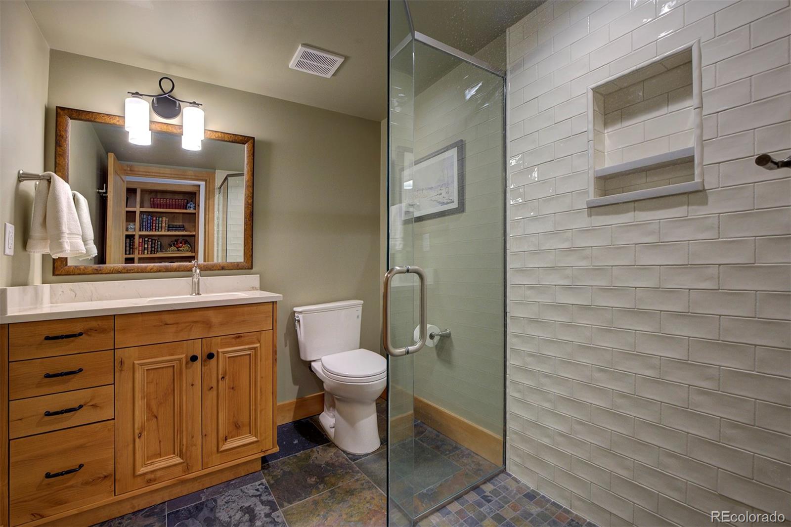 9670 South Warhawk Road Conifer, CO 80433 - Photo 21 of 40 a bathroom with a granite countertop toilet sink and mirror