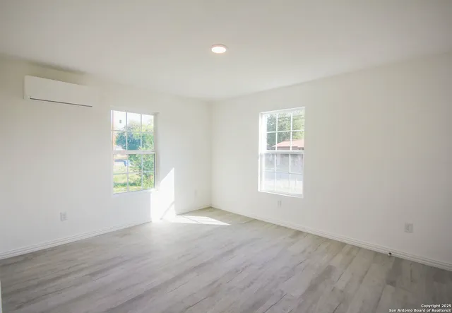 an empty room with wooden floor and windows