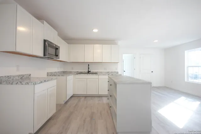 a kitchen with cabinets appliances a sink and a window