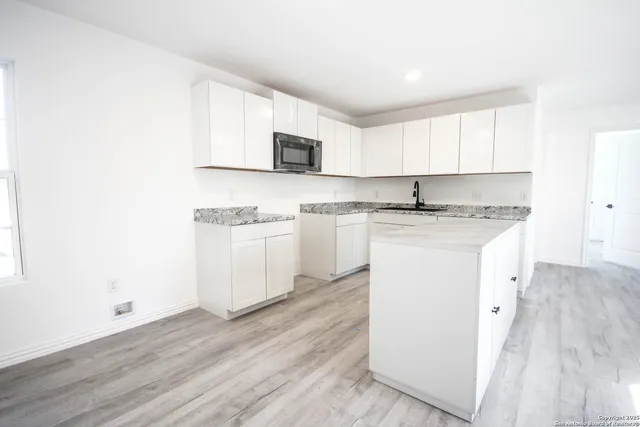 a kitchen with stainless steel appliances granite countertop a sink and cabinets with wooden floor