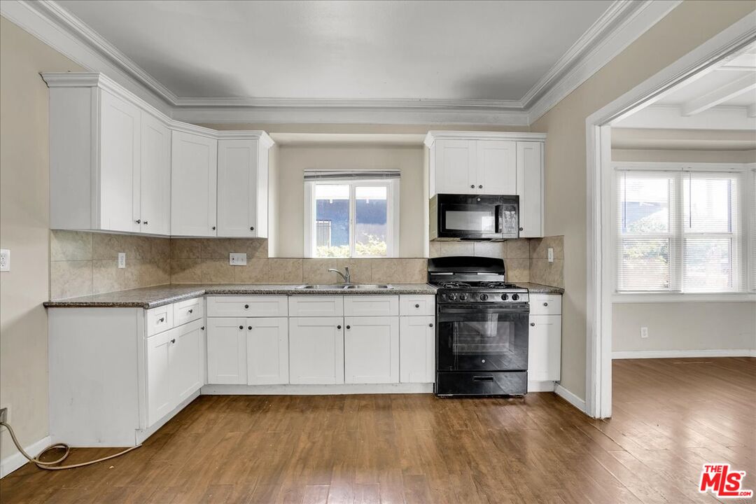 1221 West 152nd Street Compton, CA 90220 - Photo 7 of 20 a kitchen with granite countertop wooden floors and stainless steel appliances