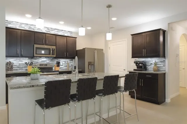 a kitchen with kitchen island granite countertop a refrigerator stove microwave and cabinets