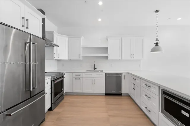 a view of kitchen with kitchen island white cabinets and stainless steel appliances