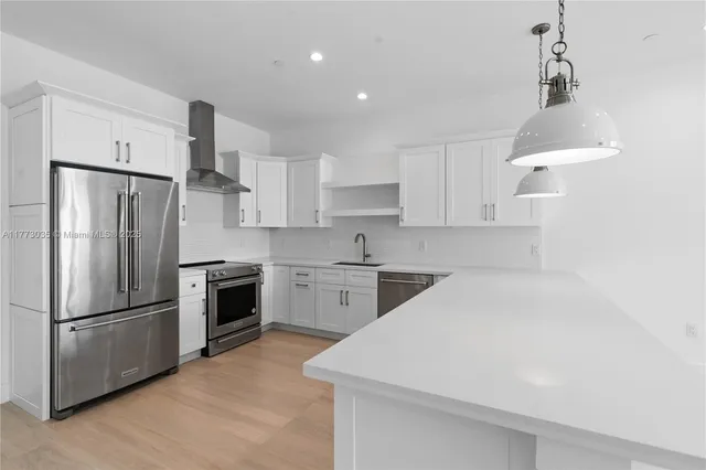 a large white kitchen with kitchen island a sink a center island a stove and a window
