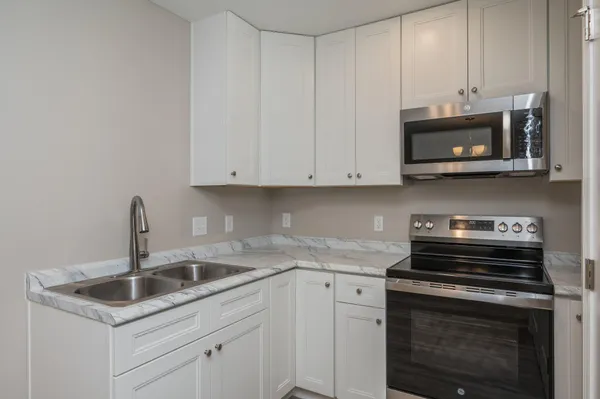 a kitchen with stainless steel appliances granite countertop white cabinets a stove a sink and dishwasher