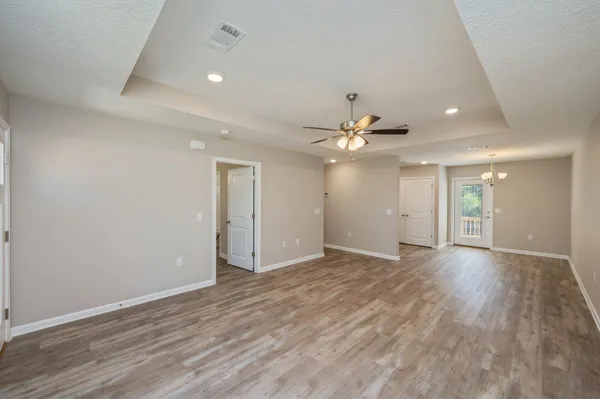a view of an empty room with wooden floor and a ceiling fan