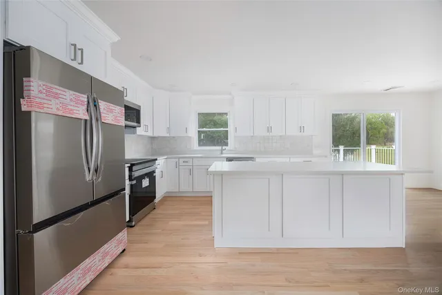a kitchen with granite countertop a refrigerator a sink and white cabinets