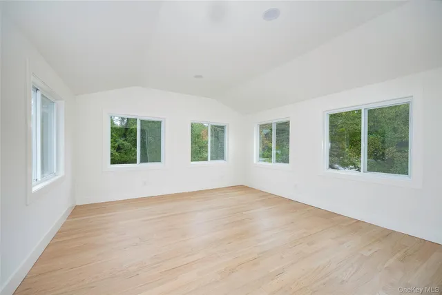 a view of an empty room with wooden floor and windows