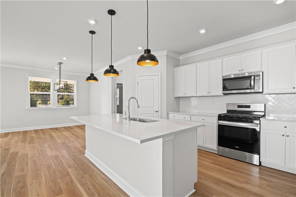 248 Nesta Grove Locust Grove, GA 30248 - Photo 15 of 40 a kitchen with kitchen island granite countertop a stove a sink a center island and wooden floor
