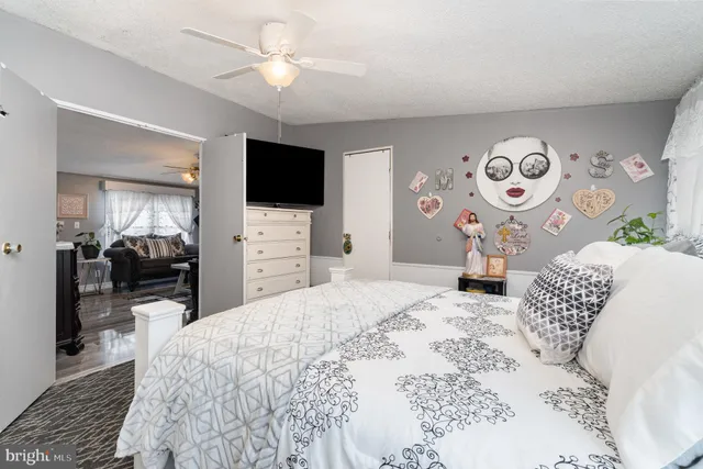 a bedroom with a large bed and a flat tv screen on dresser