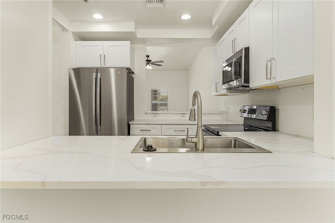 2110 West First Street, Unit 103 Fort Myers, FL 33901 - Photo 7 of 38 a kitchen with stainless steel appliances granite countertop a refrigerator and a sink