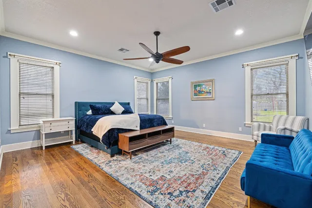 a bedroom with a bed a couch and a dresser with wooden floor