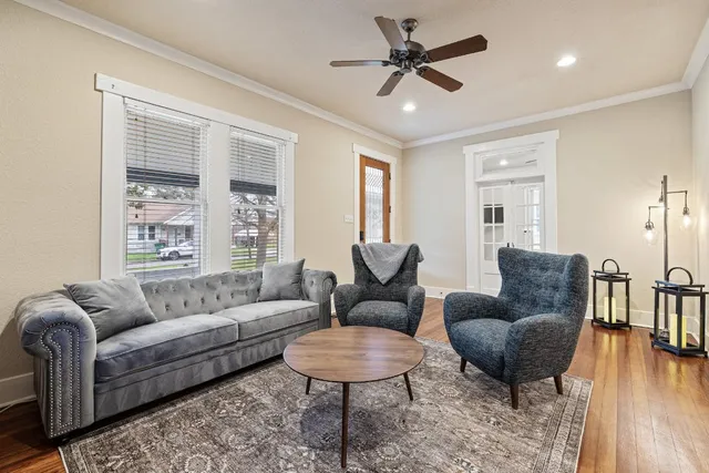 a living room with furniture a ceiling fan a rug and a large window