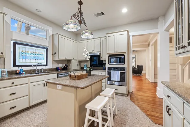 a kitchen with stainless steel appliances granite countertop a stove top oven a sink dishwasher and white cabinets with wooden floor