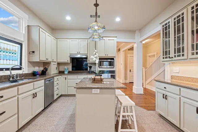 a kitchen with kitchen island granite countertop a sink counter top space appliances and cabinets