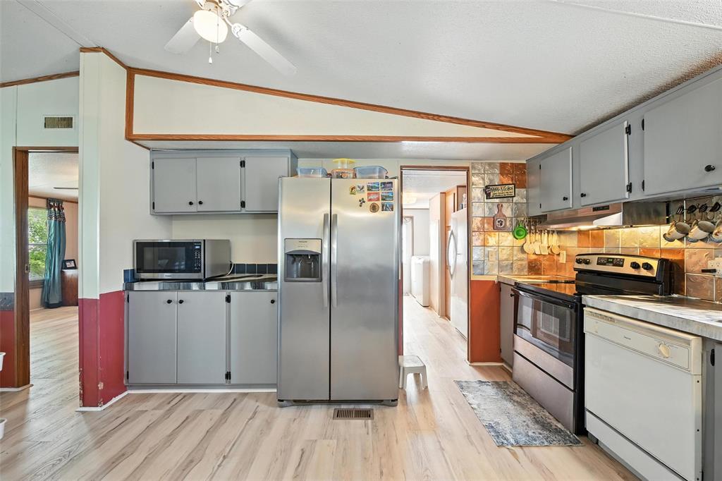 1933 Carter Road Springtown, TX 76082 - Photo 14 of 38 Kitchen featuring appliances with stainless steel finishes, vaulted ceiling, light wood-style floors, ceiling fan, and tasteful backsplash