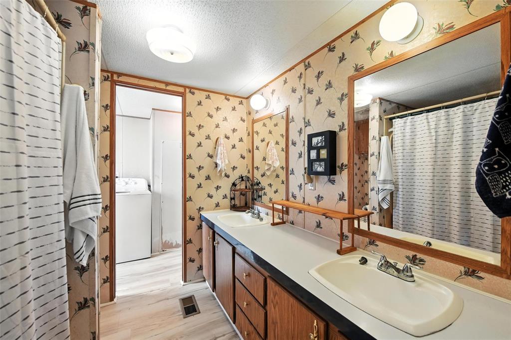 1933 Carter Road Springtown, TX 76082 - Photo 18 of 38 Bathroom featuring wallpapered walls, a textured ceiling, washer / dryer, double vanity, and wood finished floors