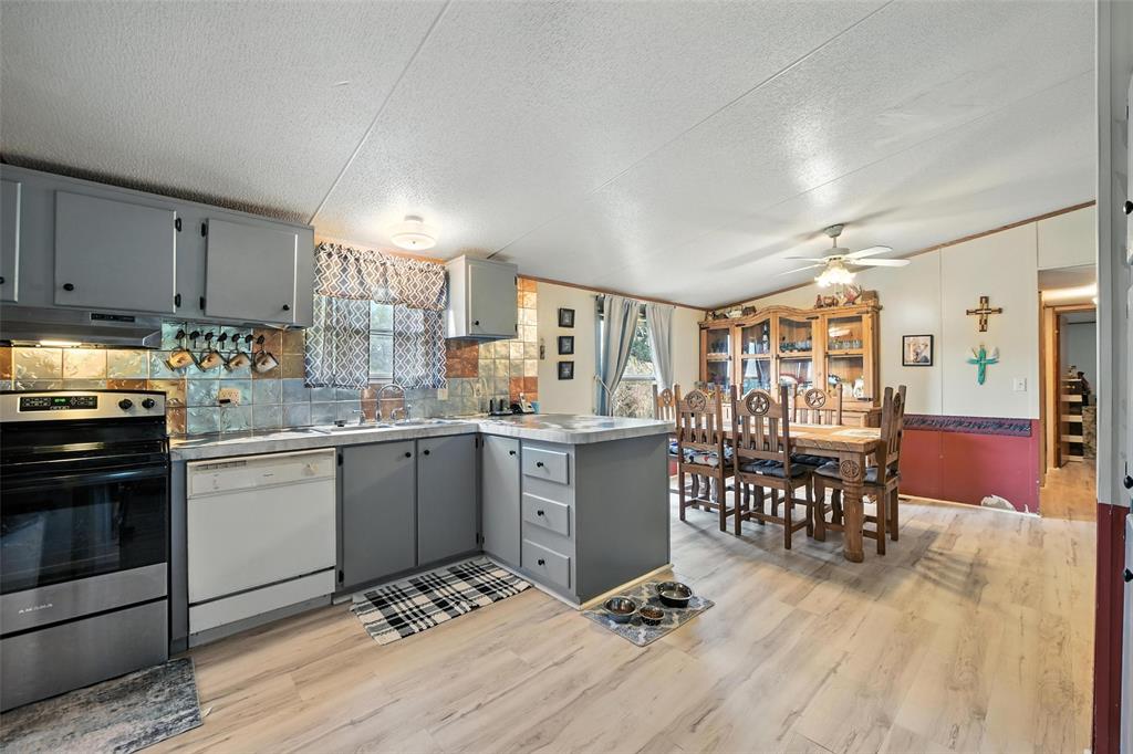 1933 Carter Road Springtown, TX 76082 - Photo 21 of 38 Kitchen featuring gray cabinets, electric stove, a textured ceiling, light wood-style floors, and white dishwasher