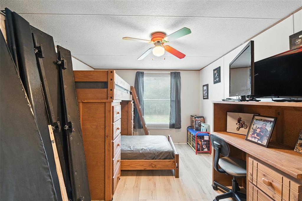 1933 Carter Road Springtown, TX 76082 - Photo 22 of 38 Bedroom with light wood-style flooring, a desk, and a textured ceiling