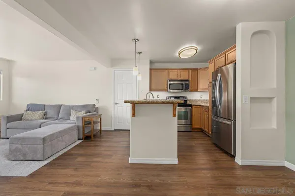 a kitchen with stainless steel appliances kitchen island wooden floors and white cabinets