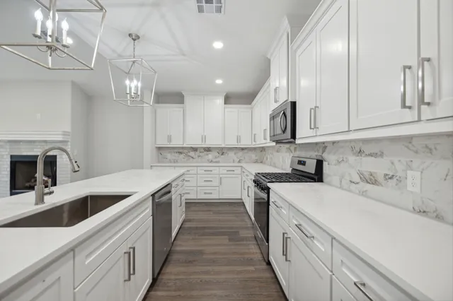 a kitchen with stainless steel appliances granite countertop a sink a stove top oven a counter space and cabinets