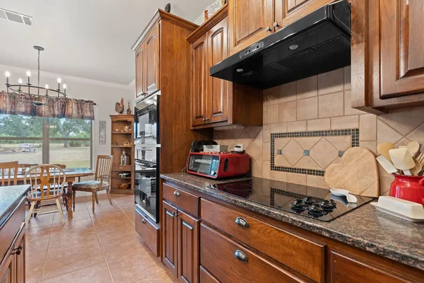 a kitchen with stainless steel appliances granite countertop a stove and a view of living room