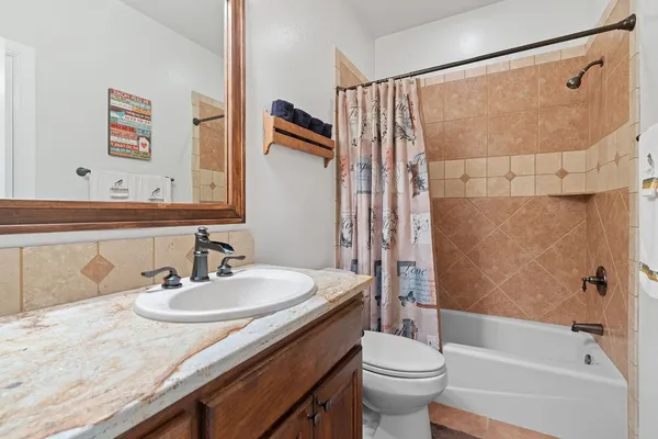 a bathroom with a granite countertop sink a toilet and shower
