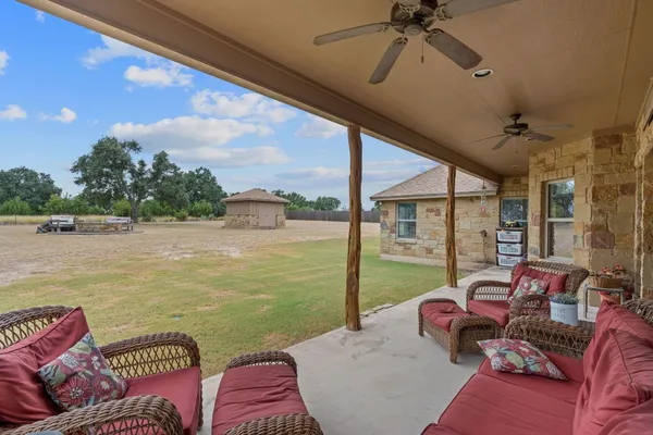 a living room with furniture floor to ceiling window and a ceiling fan