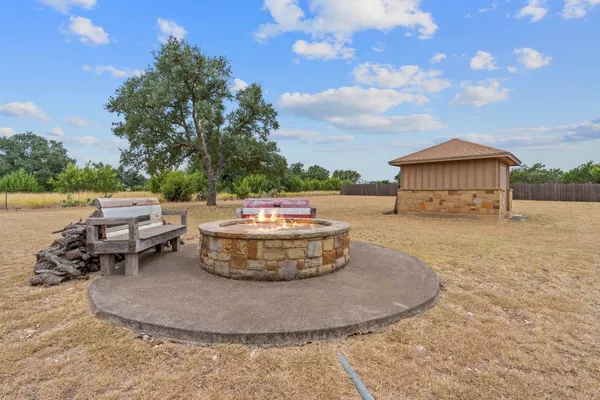 a view of a house with a yard fire pit and chairs