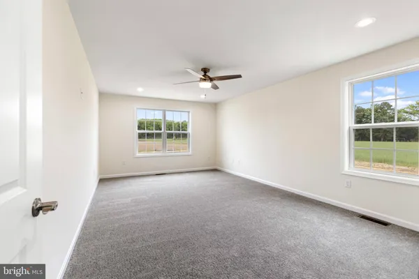 an empty room with windows and ceiling fan