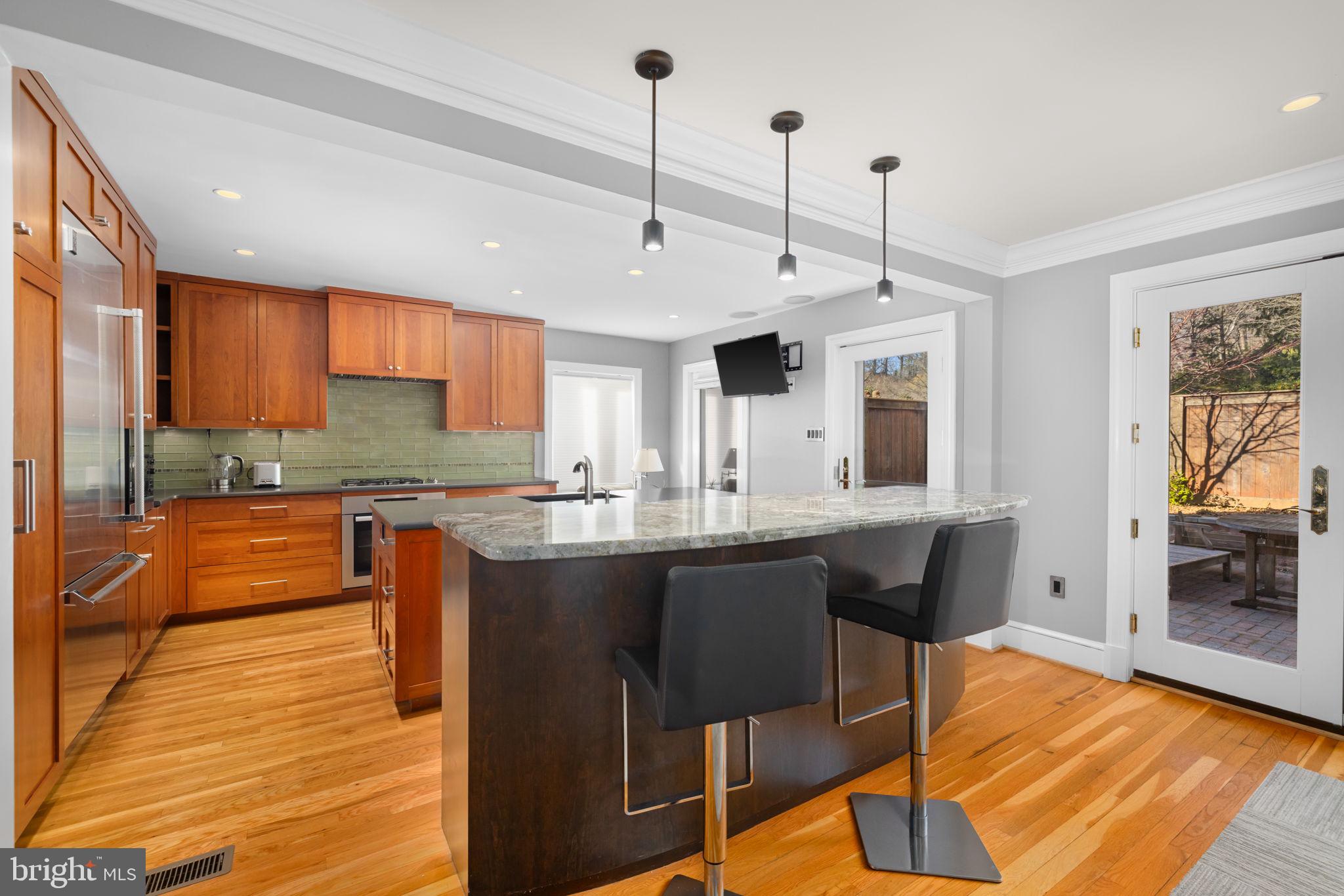 3988 Georgetown Court Northwest Washington, DC 20007 - Photo 12 of 38 a kitchen with stainless steel appliances granite countertop wooden cabinets a sink dishwasher a dining table and chairs with wooden floor